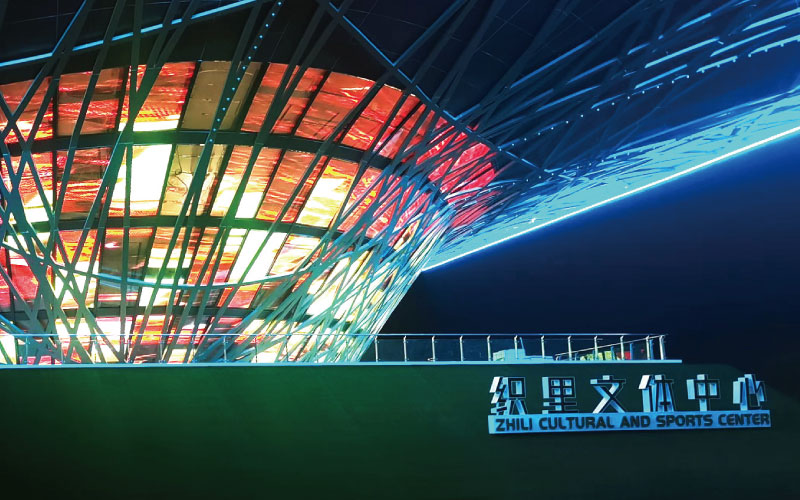 位於浙江湖州的織裏文體中心，是一座（zuò）大型異形鋼架結構建（jiàn）築。婷婷婷影院為其定製近1000平（píng）米透明屏，運用高清LED透明屏及控製係統，將其打造成了一幅巨型建築媒（méi）體立（lì）麵。